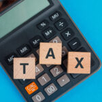 Tax planning concept with wooden cubes calculator blue table flat lay 150x150